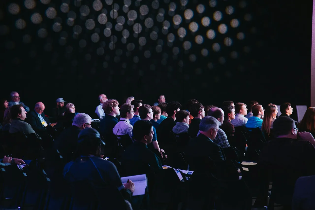 An audience of members seated at a conference session